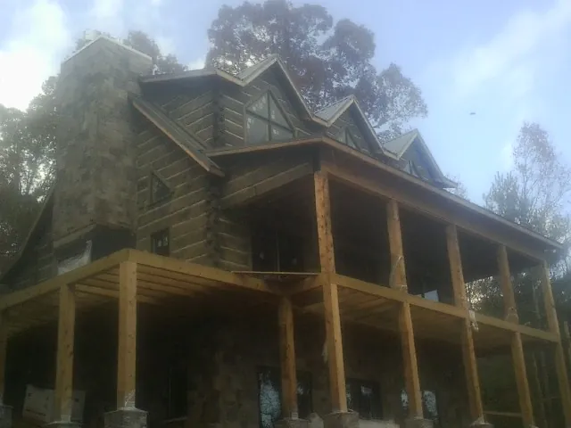 Stone chimney and dormers on a large log home with a timber porch in Pine Island