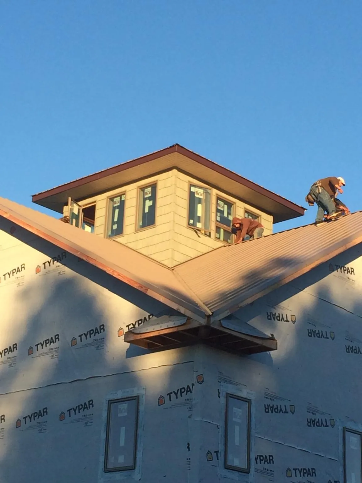 Roofers working around a rooftop cupola on a new metal roof at sunset — Roof Waterproofing in Pine Island by Roofing Brothers